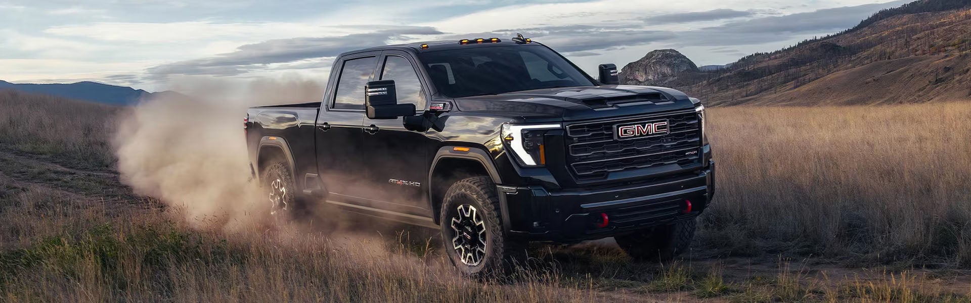 A black GMC Sierra 2500 driving through a dusty field