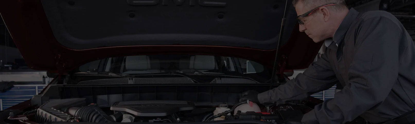 A service technician working in the engine bay of a vehicle.